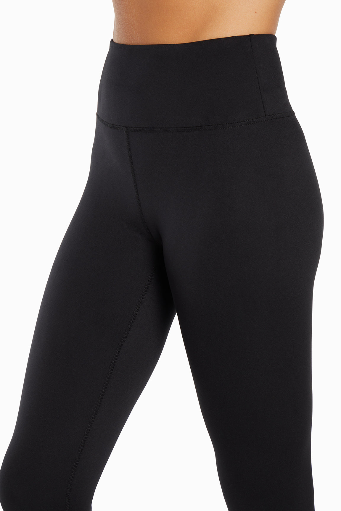 Close up front view of woman wearing black leggings on a white background.