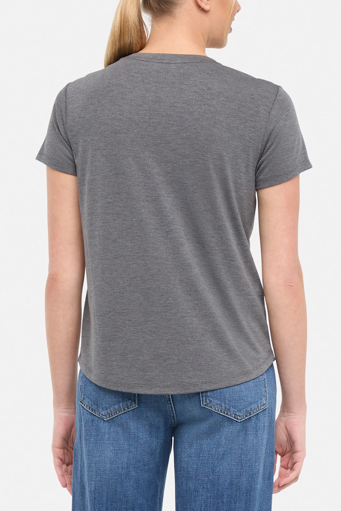 Back view of woman wearing a gray t-shirt on a white background.