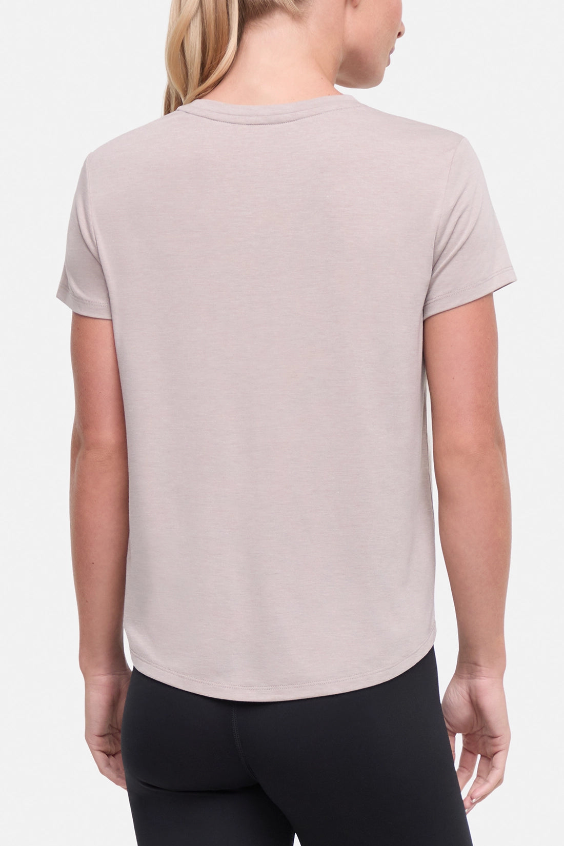 Back view of woman wearing a beige t-shirt with a graphic of an orange van and flowers on a .white background.