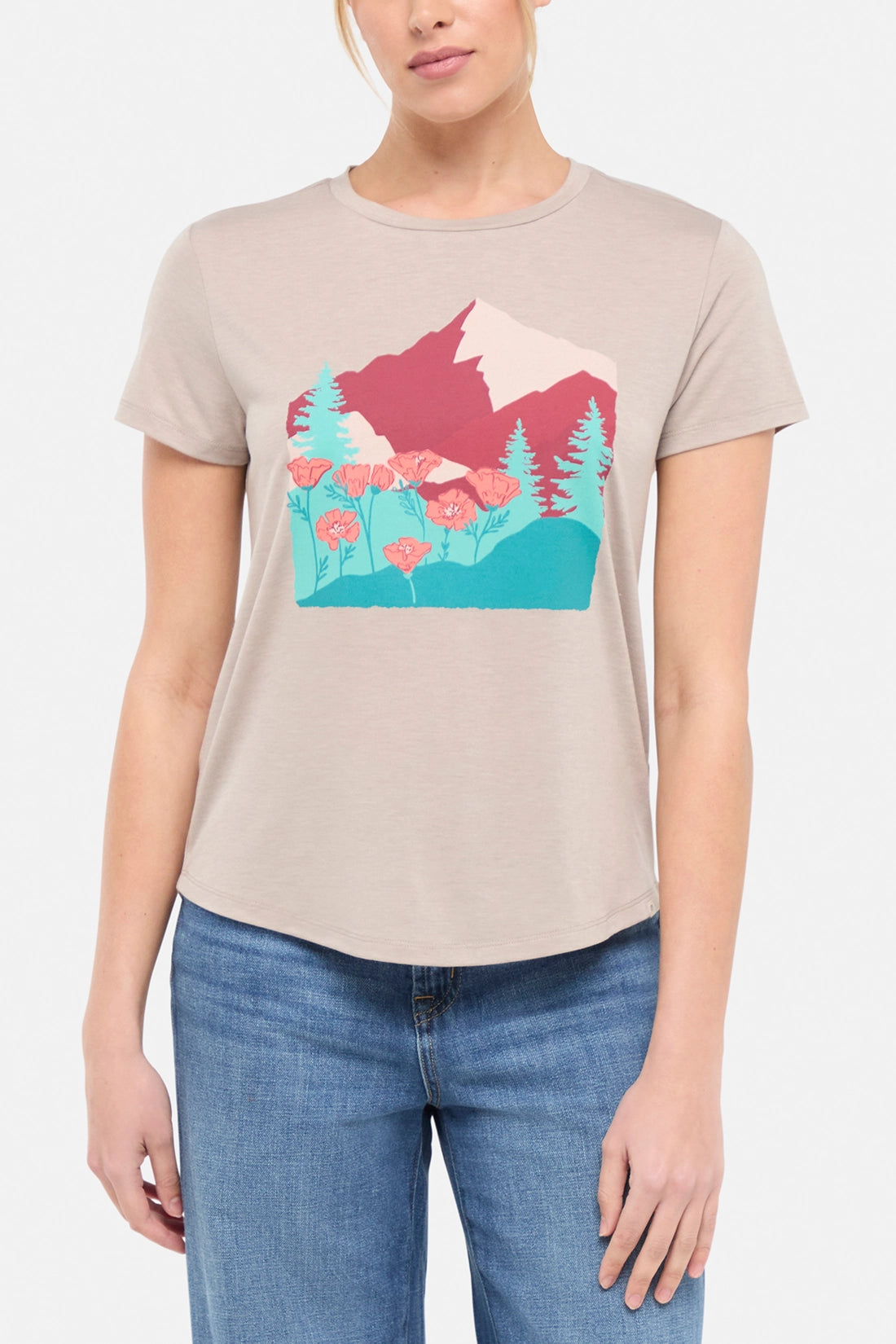 Front view of woman wearing a beige t-shirt with a graphic design of trees and poppy flowers, paired with blue jeans on white background.