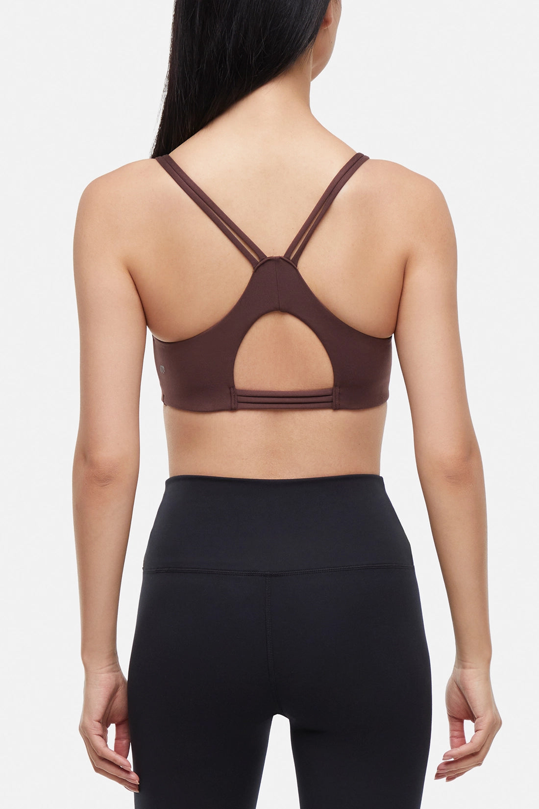 Back view of brown sports bra with crisscross straps and keyhole cutout detail on a plain background.