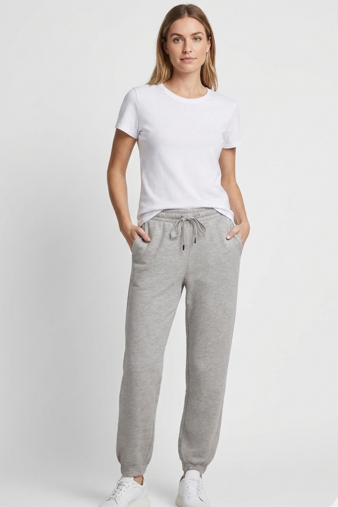 Woman wearing a white t-shirt and gray sweatpants on a white background..
