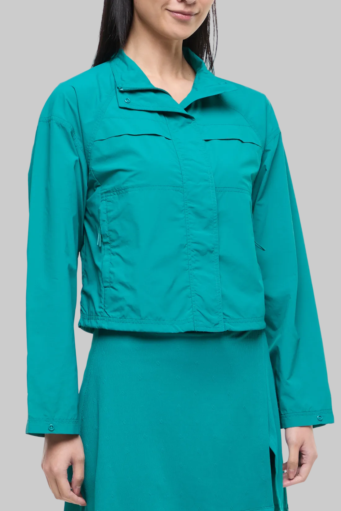 Front view of woman wearing a teal jacket and teal skirt on a white background.