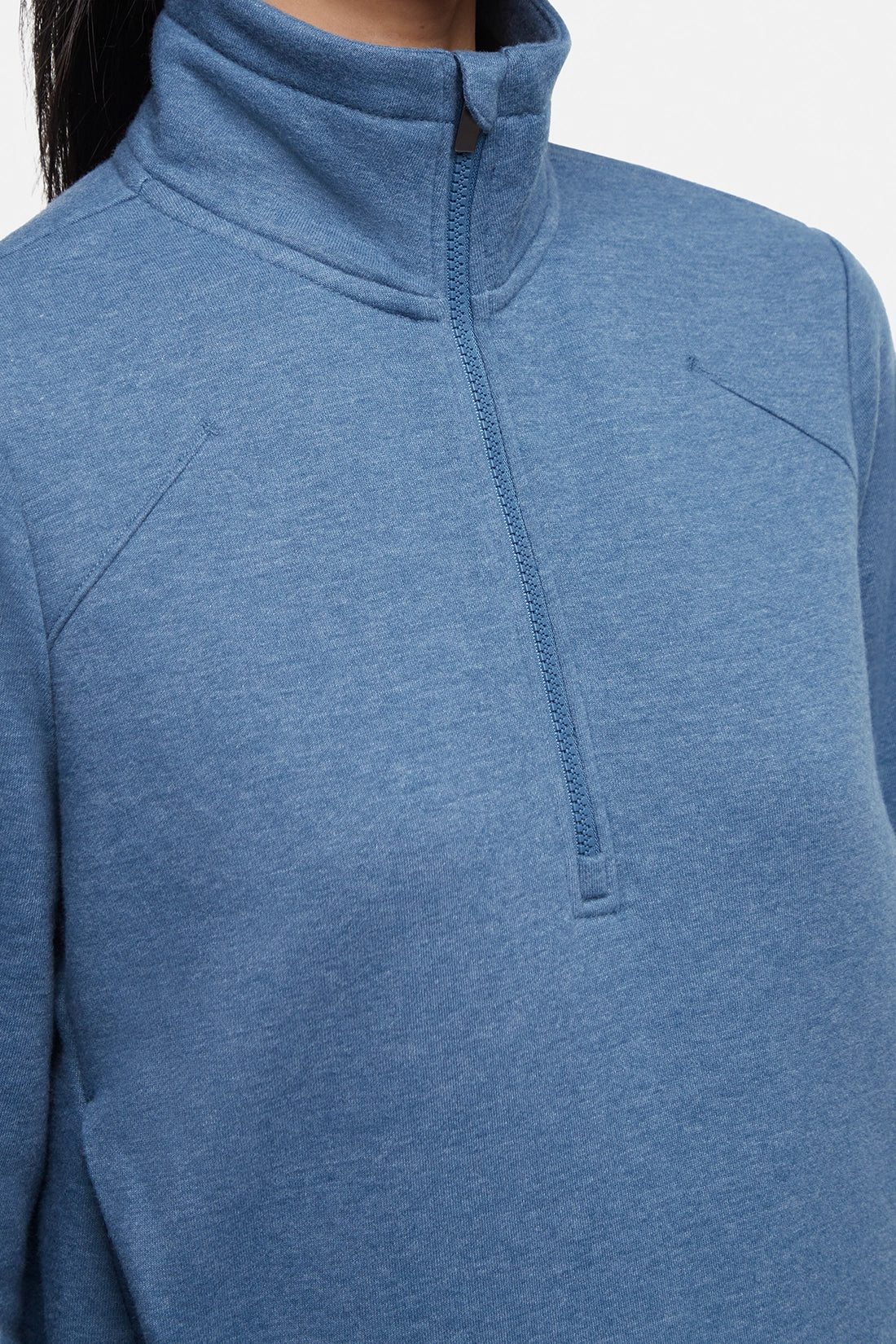 Close up front view of woman wearing heather blue half-zip pullover with thumbholes on a white background.