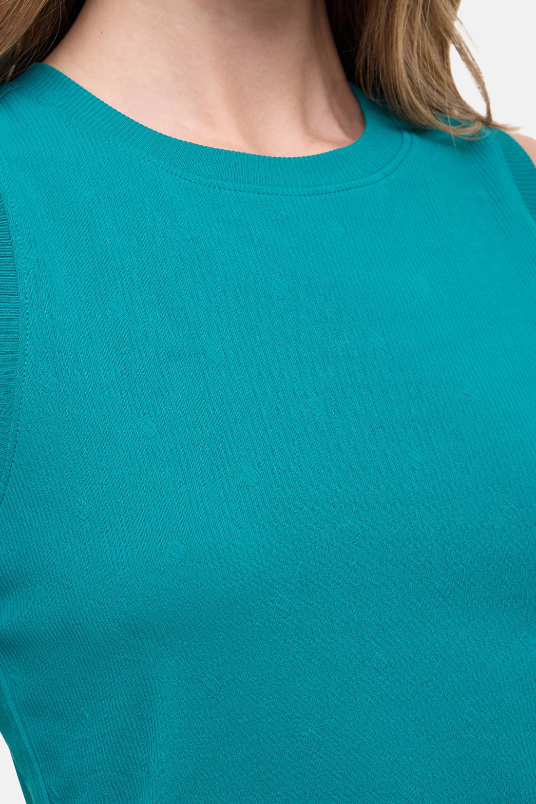 Close up front view of woman wearing a teal sleeveless top and black leggings on a white background.