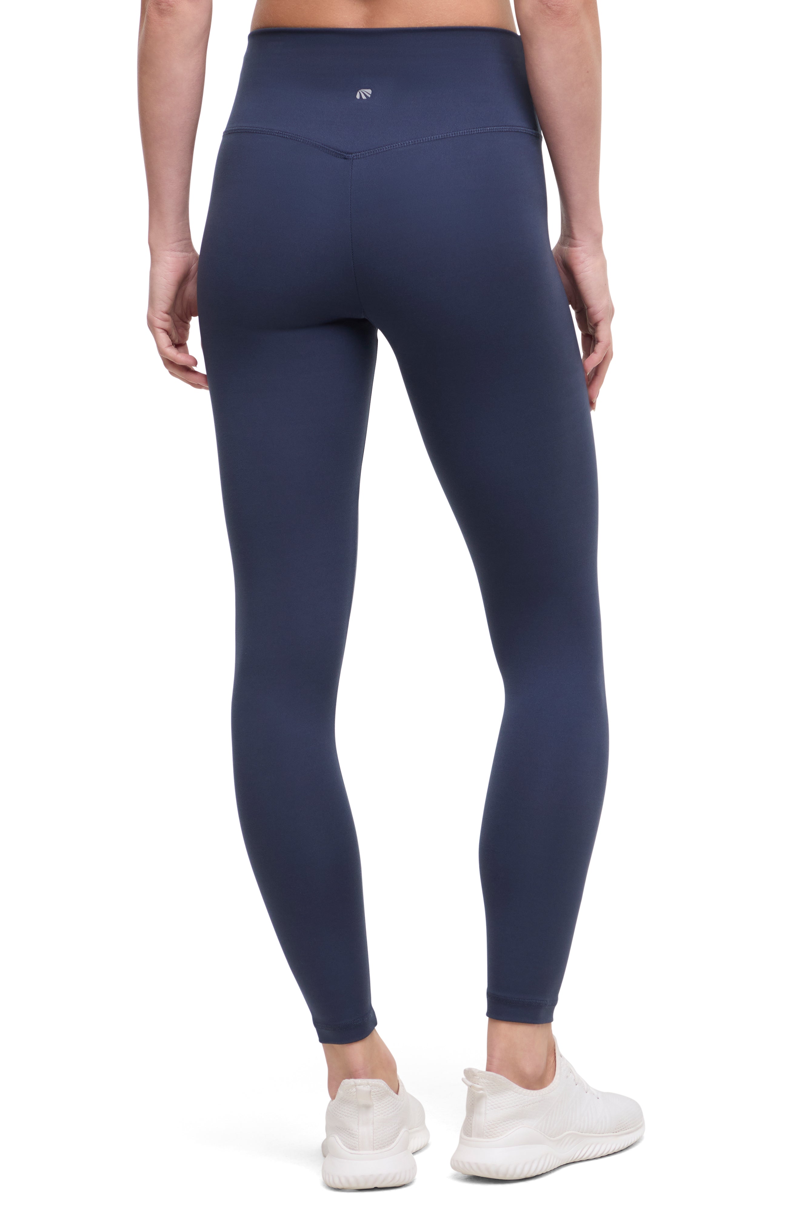 Back view of woman wearing navy leggings with a white background.