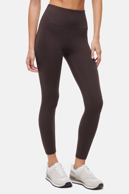 Front view of woman wearing dark brown leggings with a white background. 
