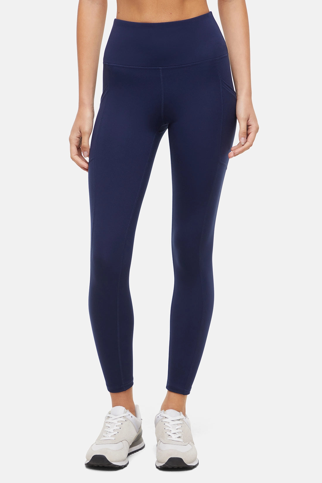 Front view of woman wearing navy leggings with a white background. 