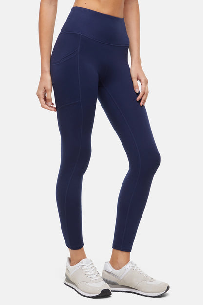 Side view of woman wearing navy leggings with a white background. 