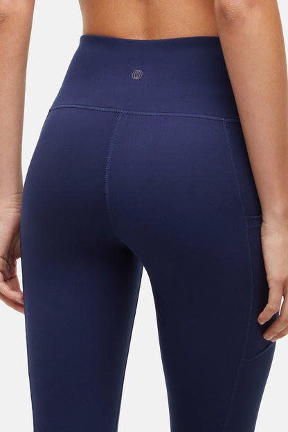 Close up back view of woman wearing navy blue leggings with a white background. 