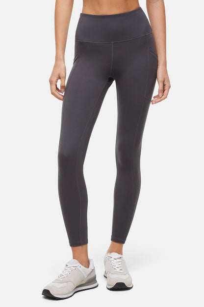 Front view of woman wearing dark gray leggings with a white background. 