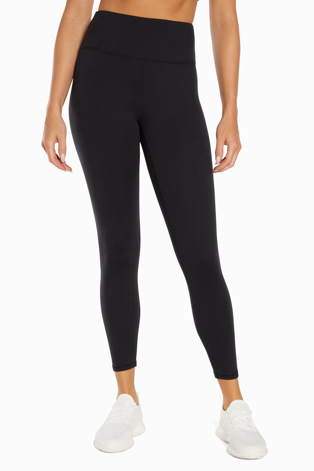 Front view of woman wearing black leggings on a white background. 