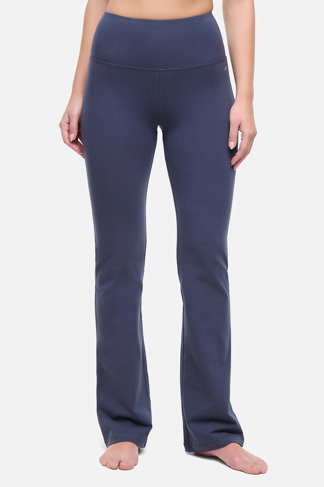 Front view of woman wearing navy blue yoga pants on a white background. 
