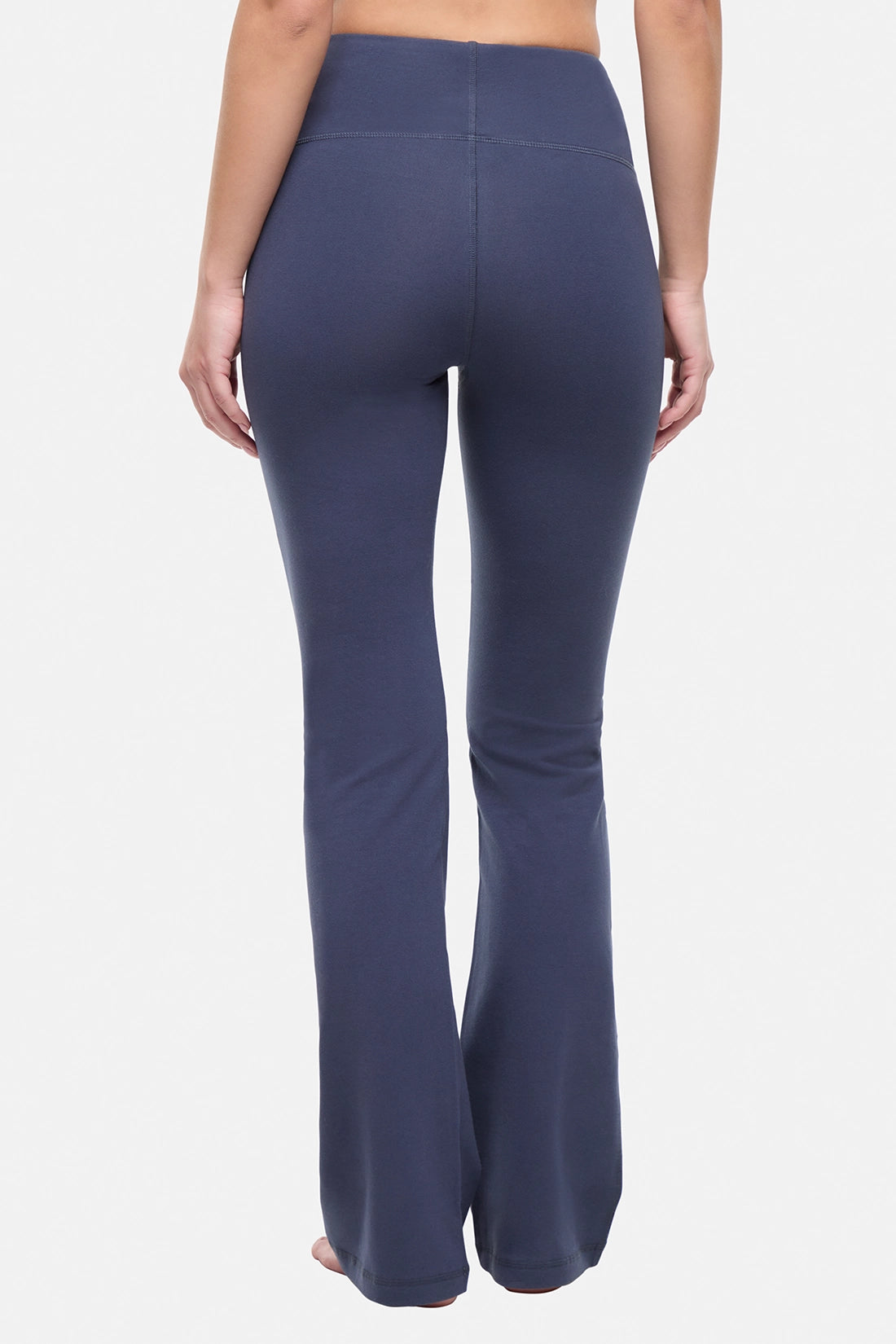 Back view of woman wearing navy blue yoga pants on a white background. 