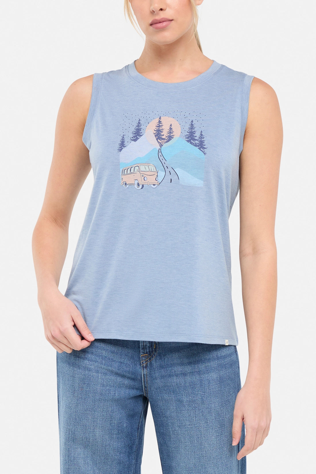 Front view of woman wearing a sleeveless light blue shirt with a graphic design of a van and mountains on white background. 