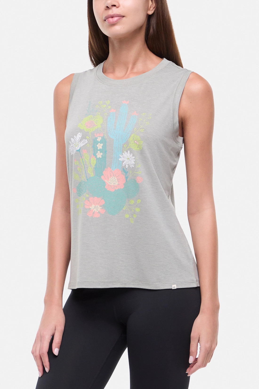 Side view of woman wearing a sleeveless gray top with colorful floral and cactus design on a white background. 