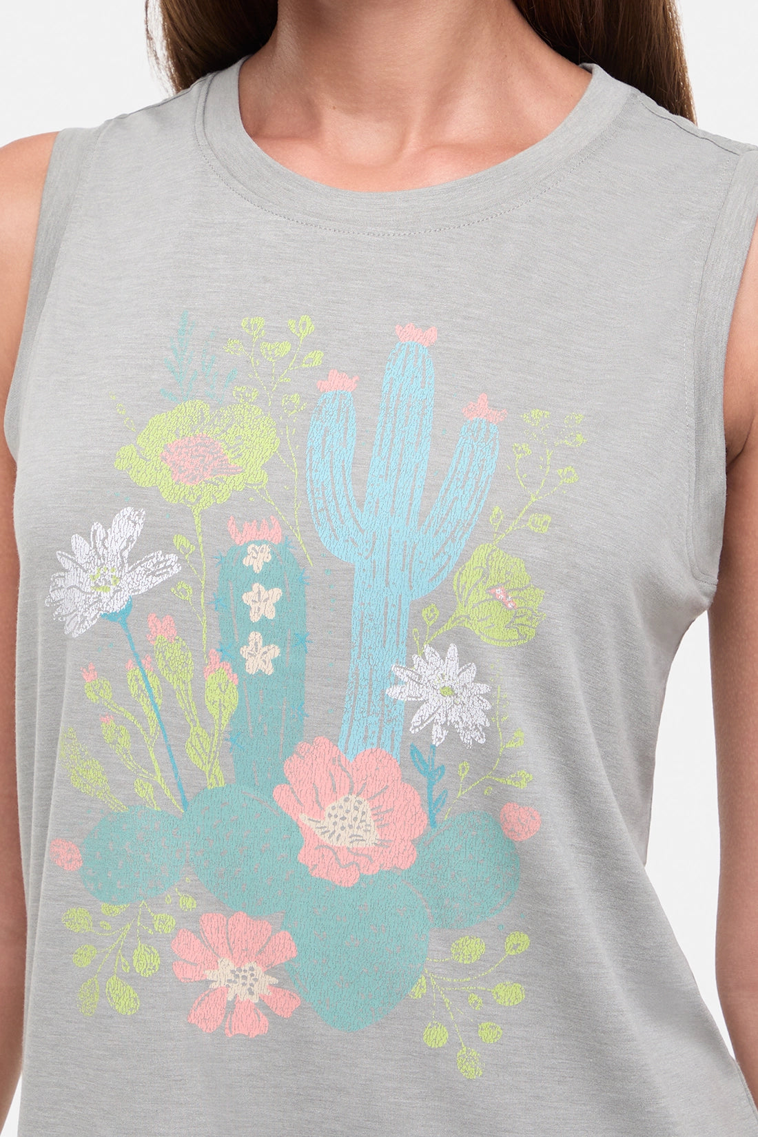 Close up view of woman wearing a sleeveless gray top with colorful floral and cactus design on a white background. 