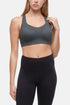 Front view of woman wearing a gray sports bra and black leggings on a white background. 