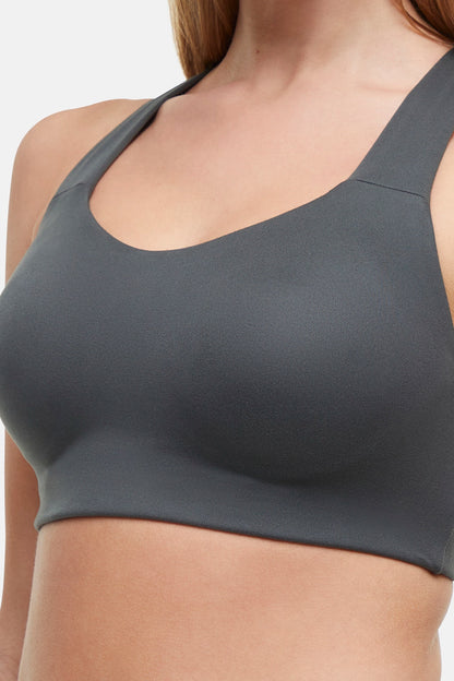 Close up front view of woman wearing a gray sports bra on a white background. 