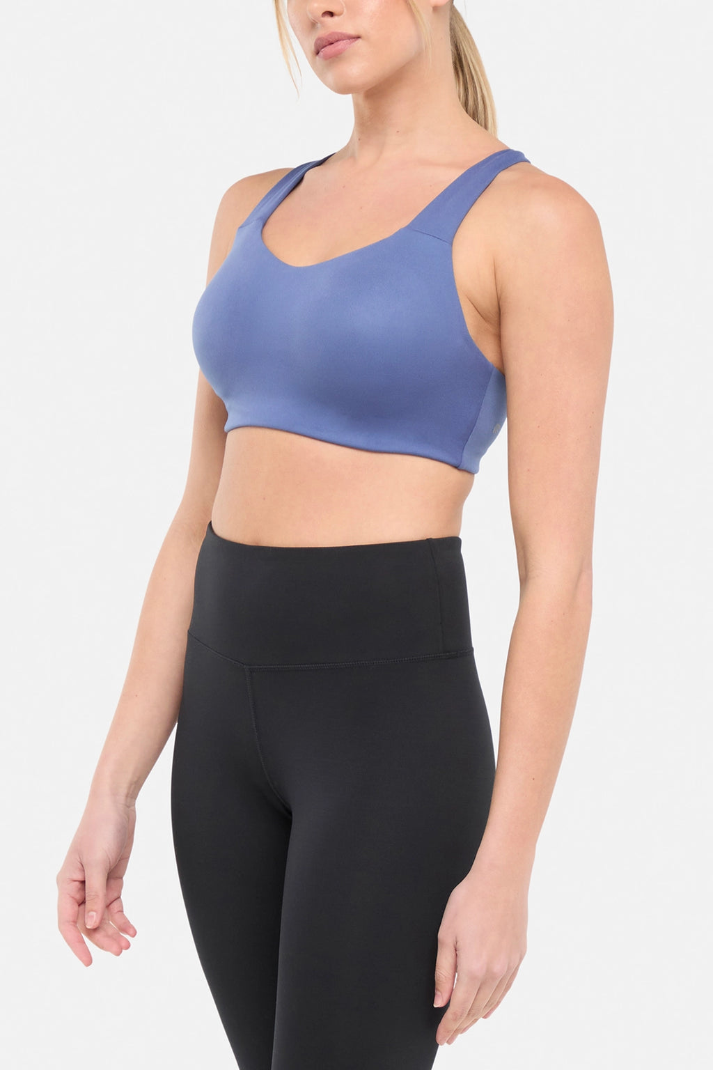 Side view of woman wearing a blue sports bra and black leggings on a white background. #color_gray-blue