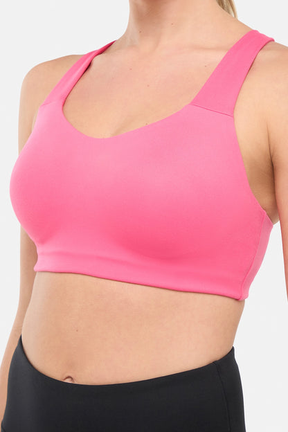 Front close up view of woman wearing a pink sports bra and black leggings on a white background. 