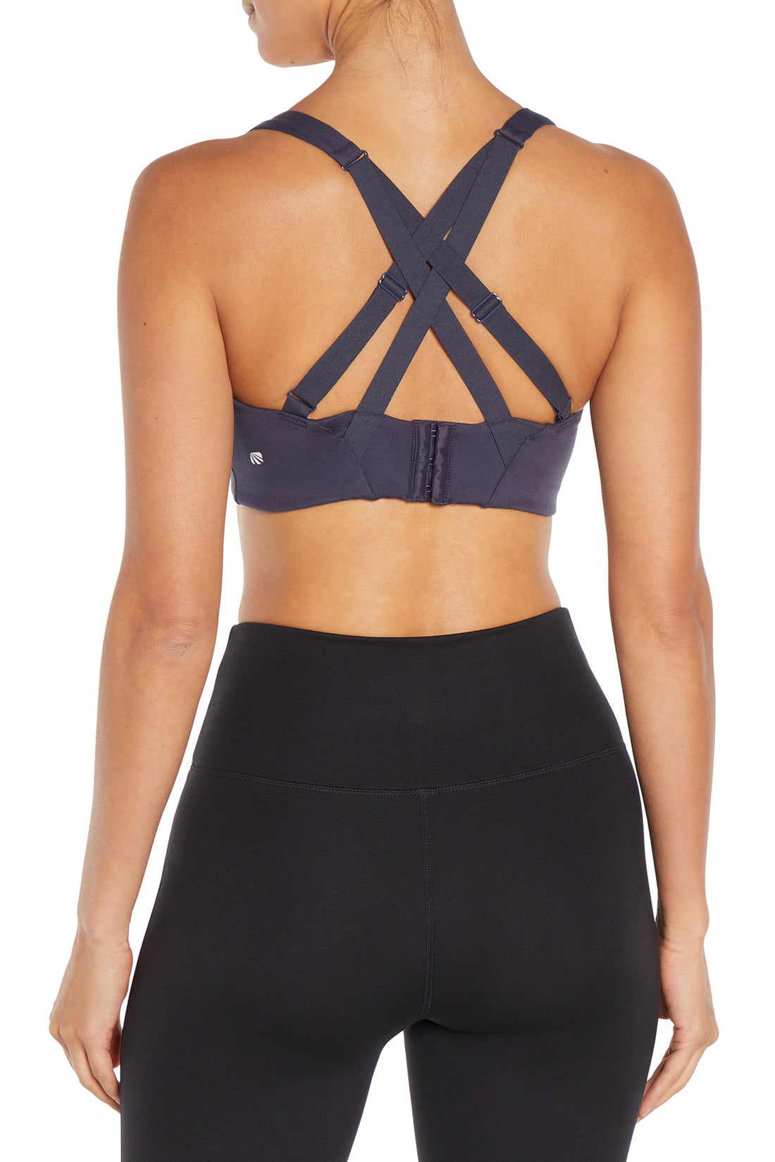 Rear view of a woman wearing a dark gray sports bra with crisscross back straps and black high-waisted leggings against a white background.  
