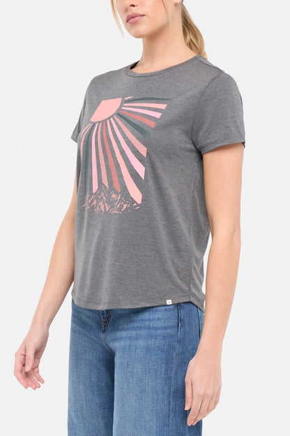 Side view of woman wearing a gray t-shirt with a pink sun and mountain graphic on a white background. 