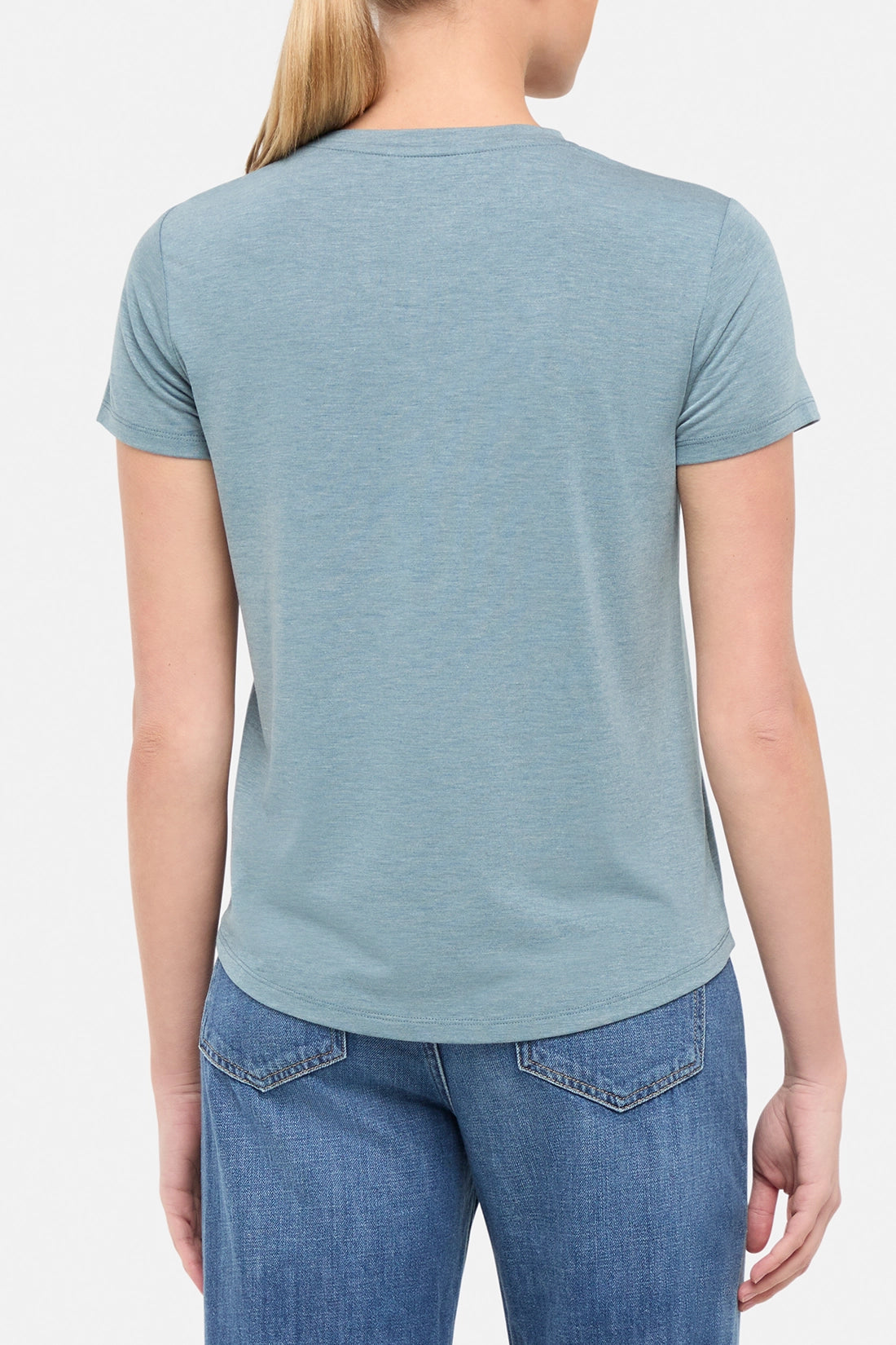 view of woman wearing a blue t-shirt  on a white background. 