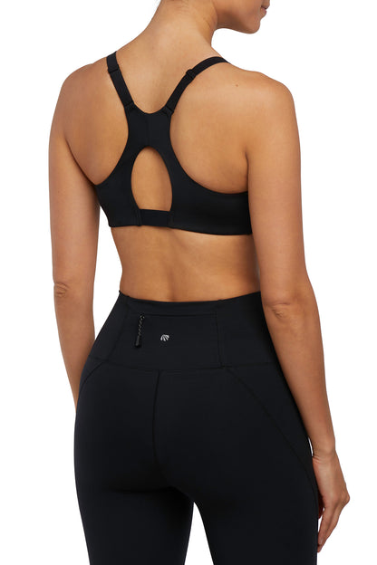 Back view of woman wearing a black sports bra and leggings on a white background. 