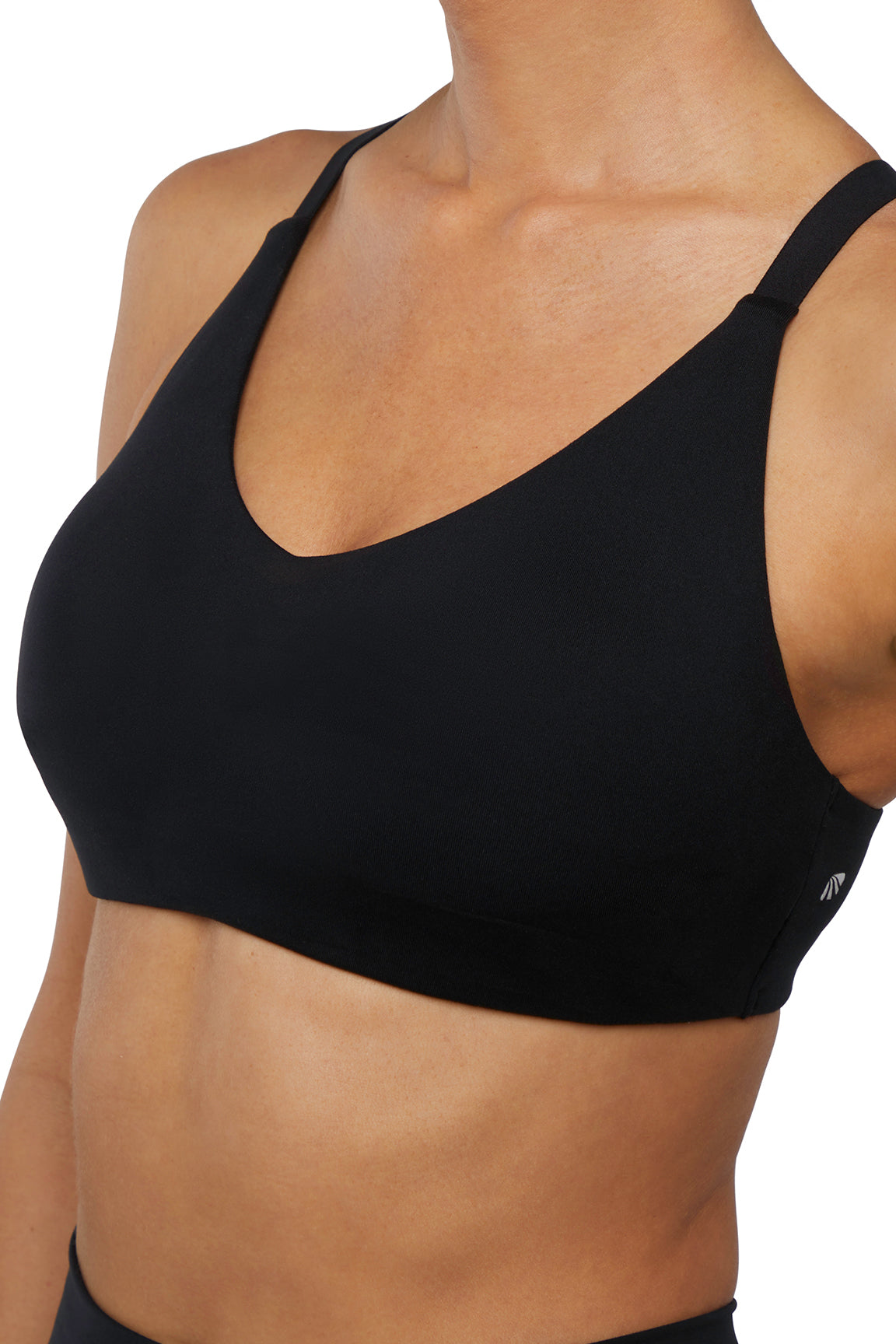 Close up front view of woman wearing a black sports bra and leggings on a white background. 