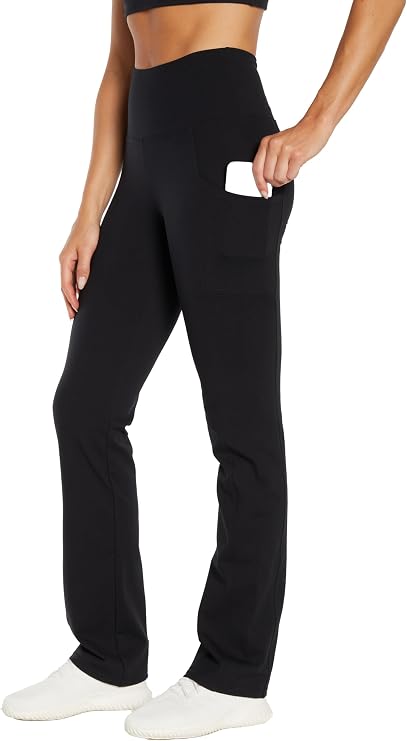 Woman wearing black high-waisted pants with hand in side pocket on a white background. #color_black