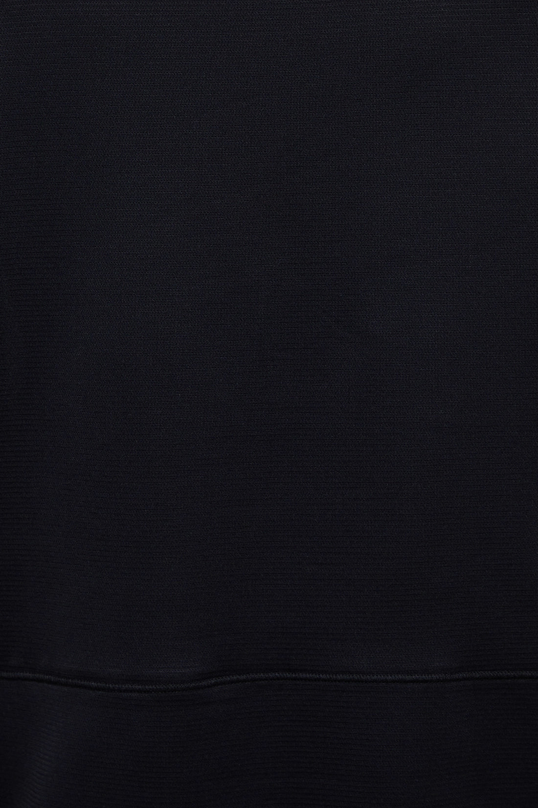 A close-up of a black ribbed fabric texture with a horizontal seam near the bottom. 