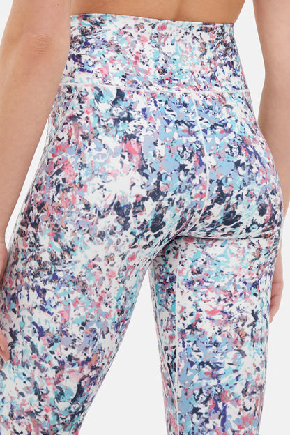 Close up back view of woman wearing colorful floral leggings on a white background. 