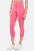Front view of woman wearing pink capris and white sneakers on a light gray background. #color_pink-flambe