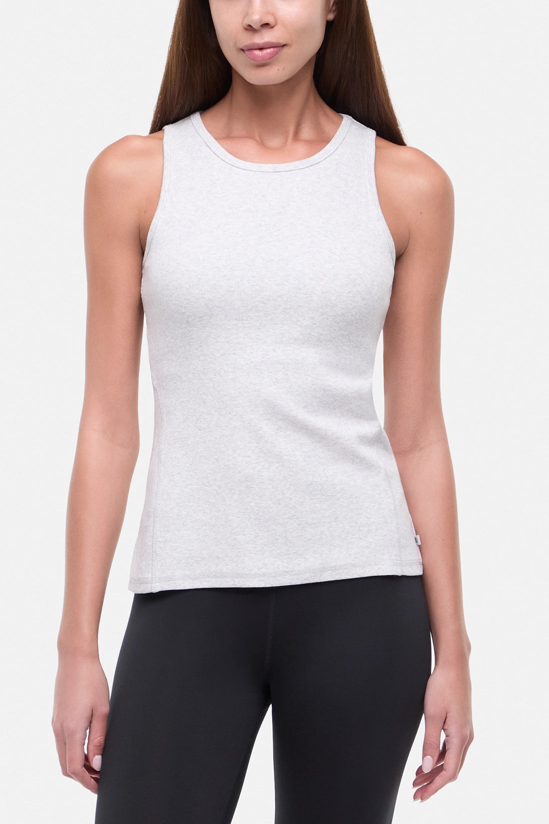 Front view of woman wearing a heather gray sleeveless tank top and black leggings on a light gray background. 