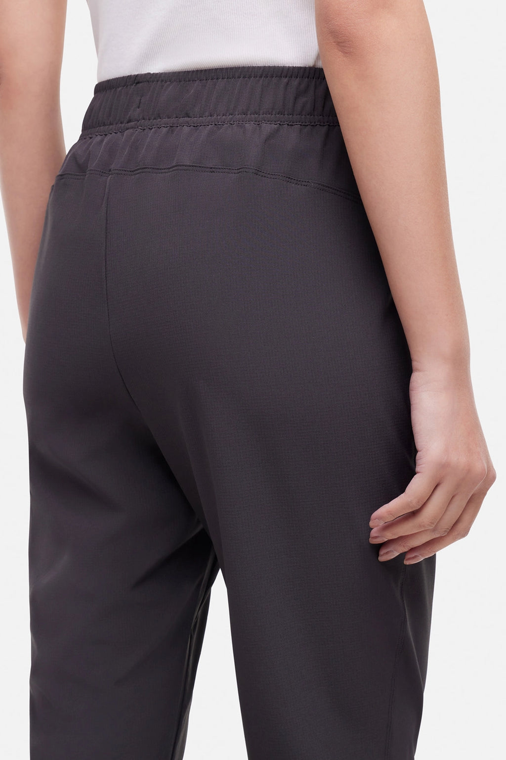 Close up back view of woman wearing black cropped pants with a white drawstring on a white background. #color_phantom