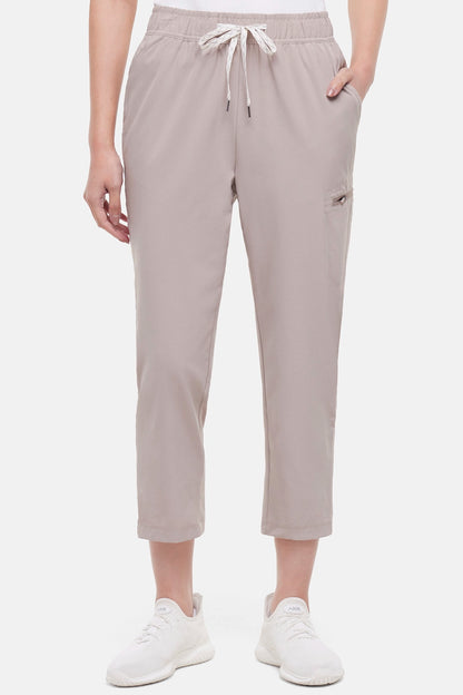 Front view of beige pants worn by a woman with hand in pocket  white drawstring waist on a white background. 