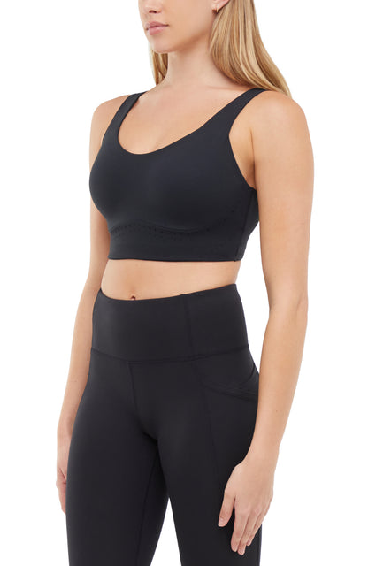 Quarter view of woman wearing a black sports bra and matching black leggings on a white background. 