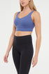 Woman wearing a blue sports bra and black leggings on a white background. 