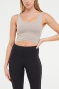 Front view of woman wearing a beige sports bra and black leggings on a white background. #color_atmosphere