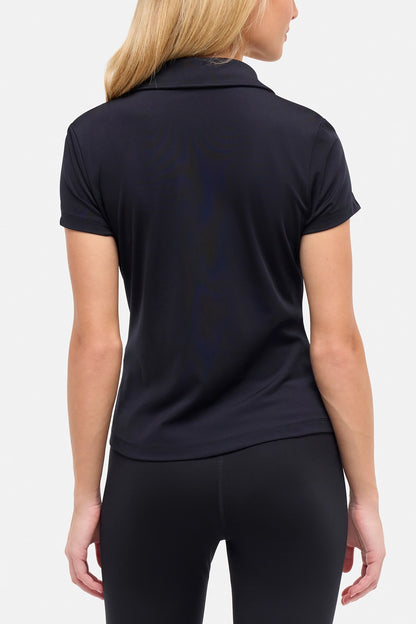 Back view of woman wearing a black polo shirt and black pants on a white background. 