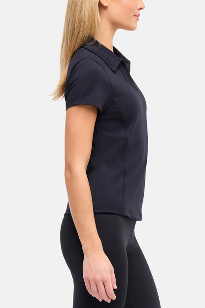 Side view of woman wearing a black polo shirt and black pants on a white background. 