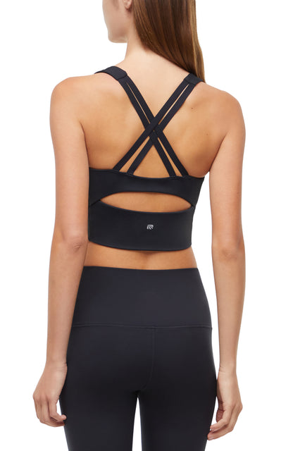 Back view of woman wearing a black sports bra with criss-cross back design and black leggings on a white background. 