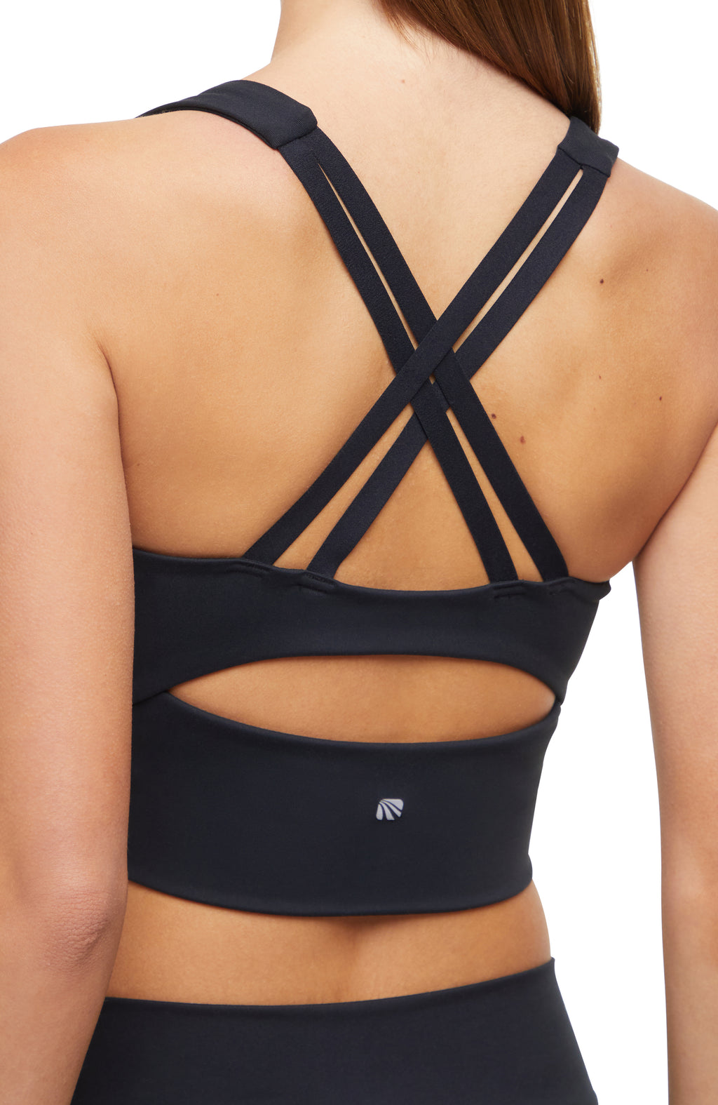 Close-up back view of woman wearing a black sports bra with criss-cross back design and black leggings on a white background. #color_black