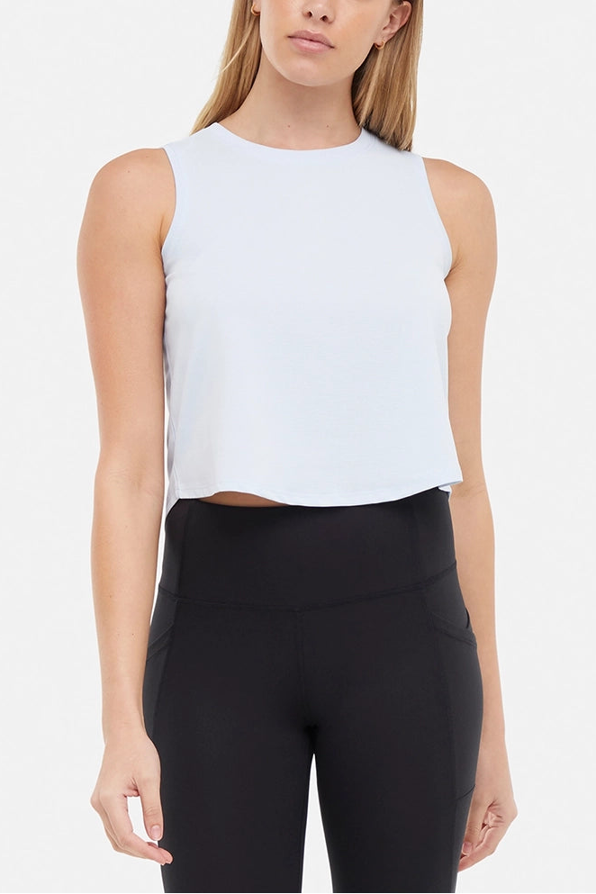 Front view of woman wearing a light blue sleeveless top and black leggings on a light gray background. 
