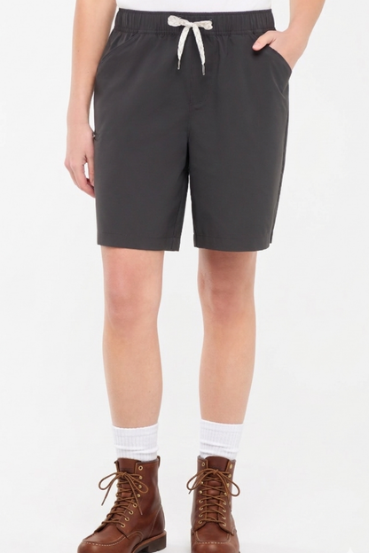 Front view of woman wearing dark gray shorts with a white drawstring, standing on a white background.