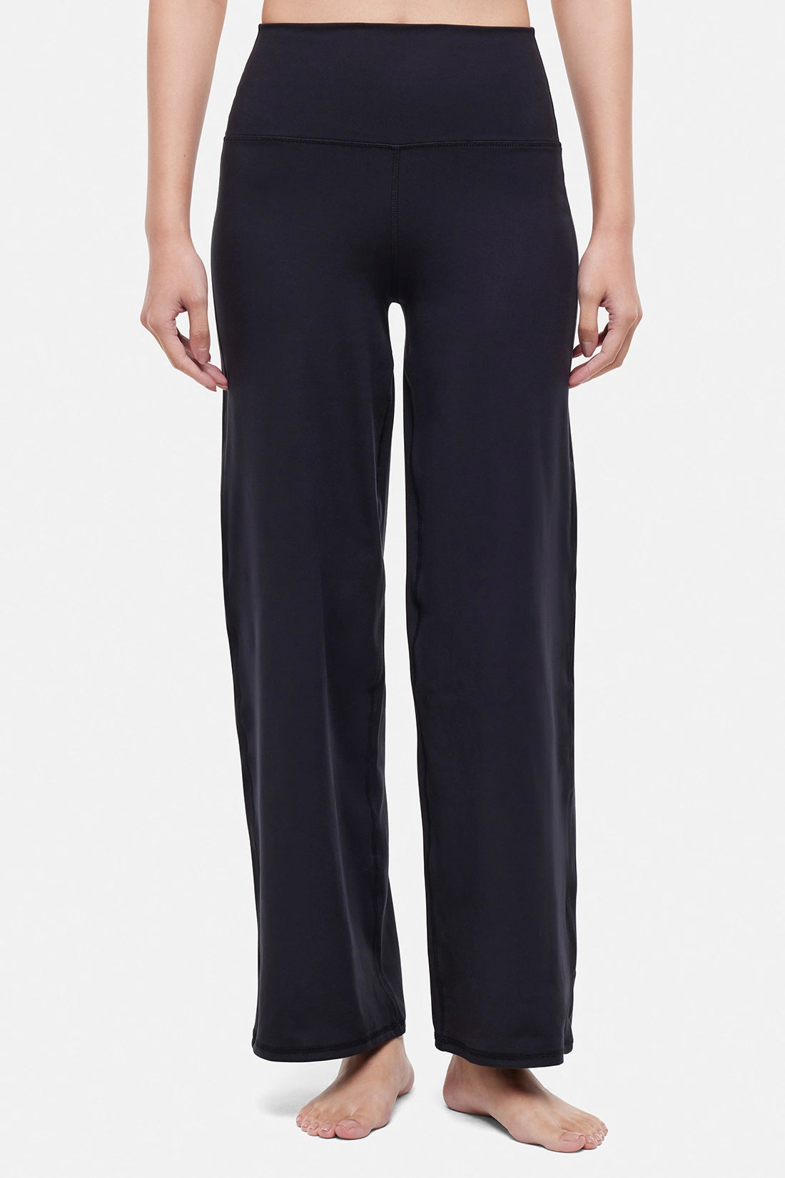 Front view of woman wearing black yoga pants on a white background. 