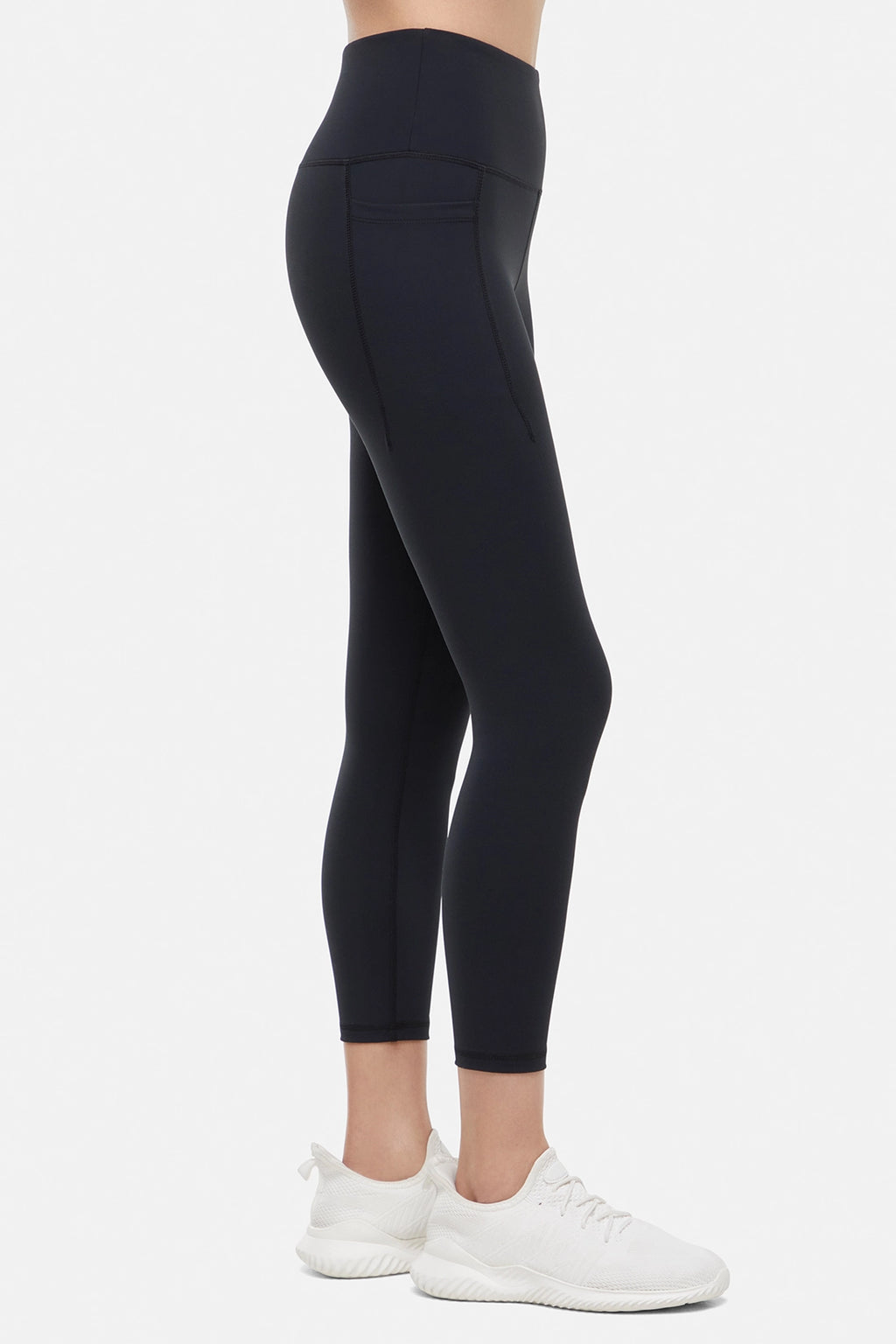 Side view of woman wearing black leggings worn by a person on a white background. #color_black