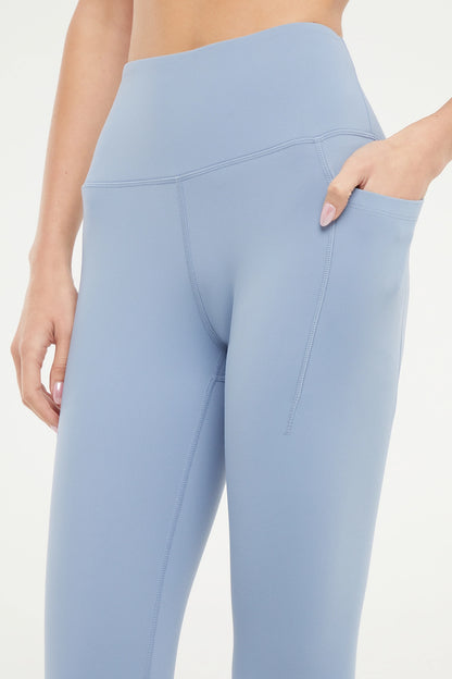 Close up front view of woman wearing light blue leggings worn by a person on a white background. 