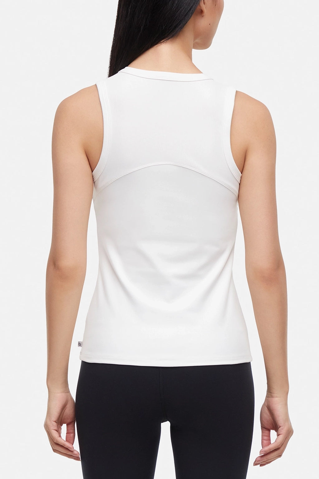 Back view of woman wearing a white ribbed-knit sleeveless tank top and black leggings on a light gray background. #color_sugar-swizzle
